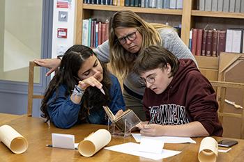 students and a faculty member examine an old book